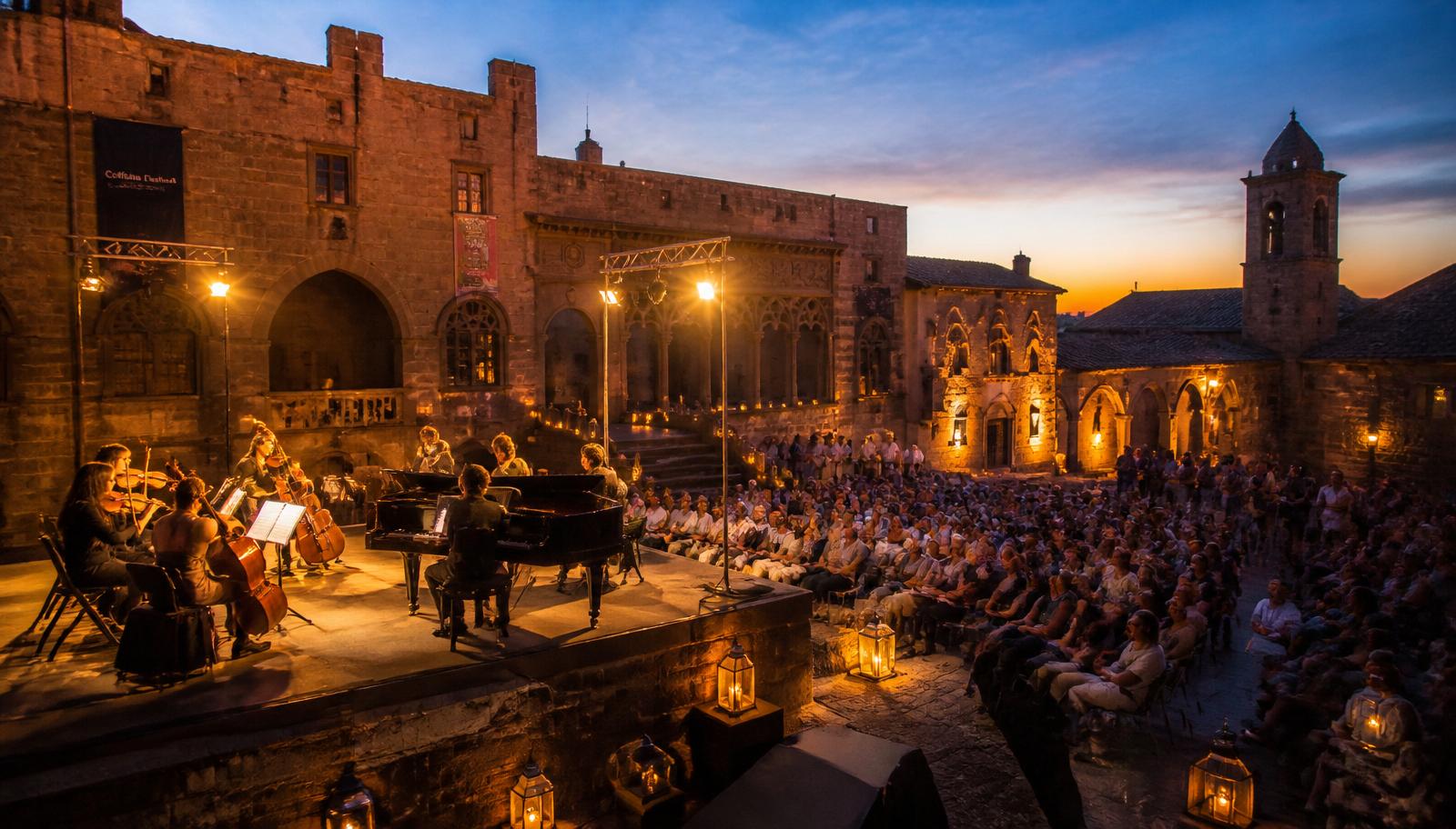 Concerto serale del festival culturale in piazza medievale del centro storico di Viterbo, pubblico e palco illuminati al tramonto